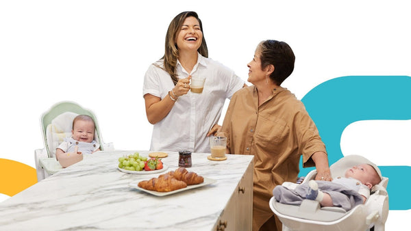 Two mothers enjoying tea together at a kitchen table with their babies nearby.
